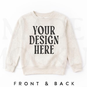 May include: A light beige crewneck sweatshirt featuring long sleeves and a ribbed collar, cuffs, and hem. The center of the chest displays the black text "YOUR DESIGN HERE" in a bold, serif font. The garment is presented against a plain background.
