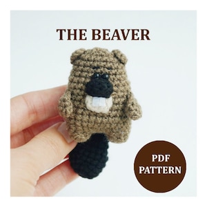 May include: Crochet pattern for a brown and black beaver amigurumi toy. The pattern is available as a PDF download. The text "THE BEAVER" and "PDF PATTERN" are visible in the image.