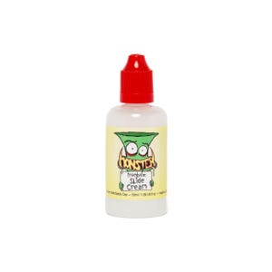 May include: A clear plastic squeeze bottle with a bright red cap containing trombone slide cream. The label features a green cartoon monster holding a sign that reads Monster Trombone Slide Cream, with a volume of 50ml / 1.69 US fl oz.