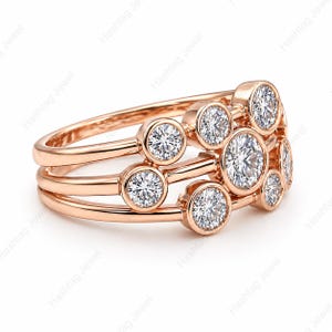 May include: Rose gold ring featuring multiple round, bezel-set diamonds. The ring has three bands with diamonds arranged in a cluster design. The diamonds sparkle against the warm metal.