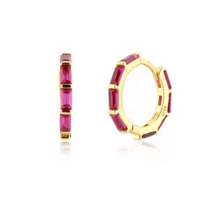 May include: Gold hoop earrings with a row of pink rectangular gemstones around the hoop.