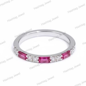 May include: A silver-toned band ring featuring an alternating pattern of rectangular baguette-cut pink gemstones and round brilliant-cut clear stones set along the front half of the band. The metal has a polished, reflective finish throughout.