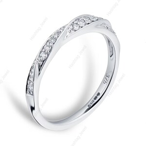 May include: A silver-colored ring with a twisted design, adorned with small, clear gemstones. The ring has a smooth, polished finish and is set against a white background. The ring is marked with the number "375".