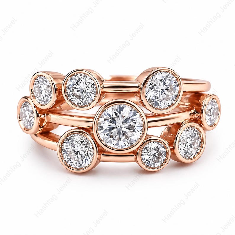 May include: Rose gold rings with multiple clear, round-cut gemstones. The rings are stacked, showcasing a variety of sizes and settings. The image is against a white background. The text "Hashtag Jewel" is visible.