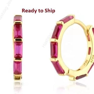 May include: Gold-colored hoop earrings with rectangular, magenta-colored gemstones. The earrings are shown in a studio setting against a white background. The text "Ready to Ship" is visible in the image.