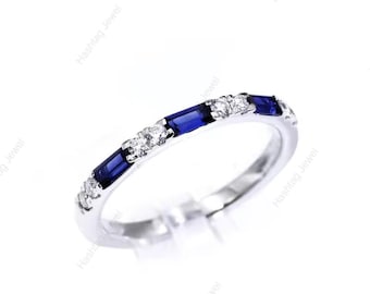 May include: A silver ring with alternating blue rectangular and round white gemstones. The ring is set on a white background, showcasing the sparkle of the gemstones. The ring is a delicate piece of jewelry.