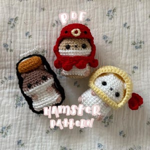 Puede incluir: Tres figuras de hámster de ganchillo hechas a mano en varios colores. Una es marrón y blanca con un contorno negro, otra es roja y la tercera es blanca con una capucha amarilla. El texto "PDF" y "HAMSTER PATTERN" son visibles.