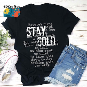 May include: Black t-shirt with white text that reads "Nature's first gold, Her hardest hue to hold. Her early leaf's a flower, But only for an hour. Then leaves turn to leaf. So Eden sank to grief, So dawn goes down to day. Nothing gold can stay."