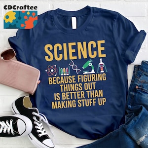May include: Navy blue t-shirt with the text "SCIENCE because figuring things out is better than making stuff up" in yellow. The shirt features science-related icons in yellow, red, and green.