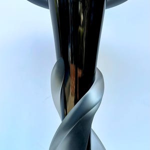 May include: A black glass vase with a wide, flared opening and a twisted, frosted glass base.