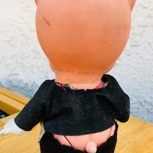 Puede incluir: Una mu&ntilde;eca de cerdo rosa con un sombrero rojo y un traje negro. La mu&ntilde;eca tiene un guante blanco en una mano y el texto "DANNER BROS. SEVEN ARTS" est&aacute; impreso en la parte posterior de la mu&ntilde;eca.