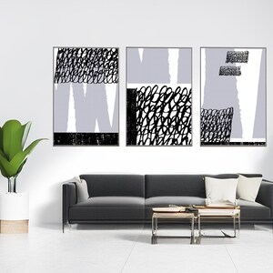Könnte beinhalten: Drei abstrakte Kunstdrucke mit schwarzen und weißen geometrischen Mustern auf weißem Hintergrund. Die Drucke sind in Schwarz gerahmt und an einer weißen Wand über einem schwarzen Sofa aufgehängt.