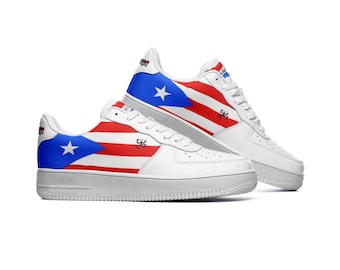Puede incluir: Zapatillas blancas de caña baja con un diseño de bandera puertorriqueña roja, blanca y azul. La bandera está en el lateral de la zapatilla y los cordones son blancos.