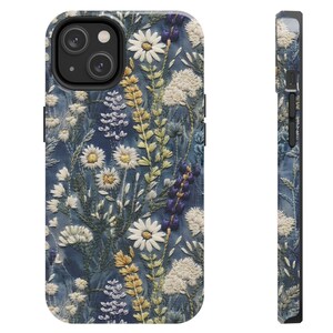 Op de afbeelding: Een blauwe telefoonhoes met een geborduurd bloemenpatroon. De bloemen zijn wit, geel en paars. De hoes is gemaakt van duurzaam materiaal en is ontworpen om je telefoon te beschermen tegen krassen en vallen.