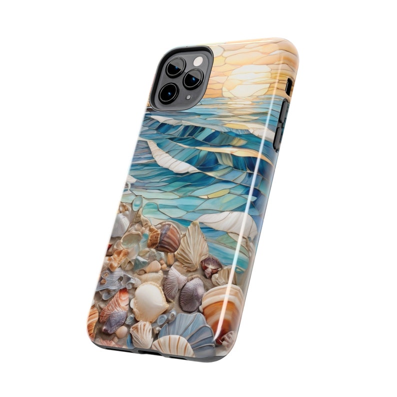 May include: A smartphone case featuring a printed design of a beach scene with a sunset over blue ocean waves and a collection of various seashells in shades of white, tan, brown, and grey scattered across the sandy foreground of the image.