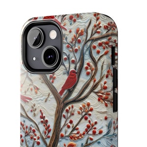 May include: A phone case with a wintery design featuring a red cardinal perched on a branch with red berries. The background is a white and blue patterned design.
