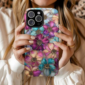 K&ouml;nnte beinhalten: Eine Smartphone-H&uuml;lle mit einem farbenfrohen Blumenmuster im Buntglas-Stil, das &uuml;berlappende Bl&uuml;tenbl&auml;tter in Magenta, T&uuml;rkis und zartem Pfirsich zeigt. Dunkle Umrandungen um jede Bl&uuml;te erzeugen eine segmentierte Optik wie bei einem Mosaik.