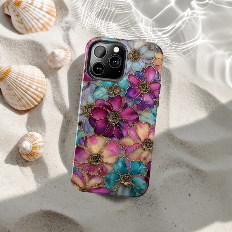 K&ouml;nnte beinhalten: Eine Smartphone-H&uuml;lle mit einem lebendigen, mehrfarbigen Blumenmuster in Magenta, T&uuml;rkis und sanftem Gelb. Das Design zeigt filigrane, goldfarbene Umrandungen um jedes Bl&uuml;tenblatt sowie eine Aussparung f&uuml;r die Kameralinse oben.