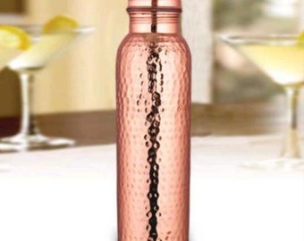 Könnte beinhalten: Eine gehämmerte Kupfer-Wasserflasche mit Deckel. Die Flasche ist hellkupferfarben und hat eine gehämmerte Textur.
