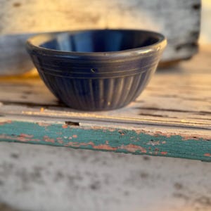 May include: A deep blue ceramic bowl featuring a rounded rim and a series of vertical ridges or fluted detailing around the exterior base. The bowl has a smooth, glossy finish and a consistent dark blue color throughout its entire surface area.