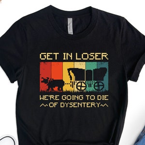 Op de afbeelding: Zwart T-shirt met een vintage-stijl grafische afbeelding van een gedekte wagen en de tekst "GET IN LOSER WE'RE GOING TO DIE ~OF DYSENTERY~"