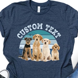May include: A navy blue t-shirt with a vintage sunset graphic and four dogs. The text "CUSTOM TEXT" is printed on the shirt.