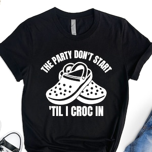 May include: Black t-shirt with white text that reads "THE PARTY DON'T START 'TIL I CROC IN". The text is accompanied by a graphic of a pair of white Crocs.