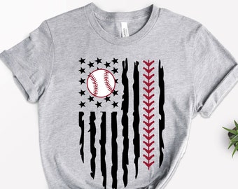 May include: A light gray t-shirt featuring a baseball-themed design. The design resembles an American flag, with a baseball replacing the stars and the seams of a baseball replacing the stripes. The shirt has rolled-up sleeves and a knotted hem.