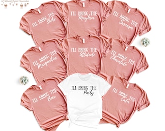 Puede incluir: Una colección de camisetas rosas y blancas con frases blancas. Las frases incluyen "I'll Bring the Shots", "I'll Bring the Mayhem" y "I'll Bring the Sarcasm". Las camisetas están dispuestas sobre un fondo blanco.
