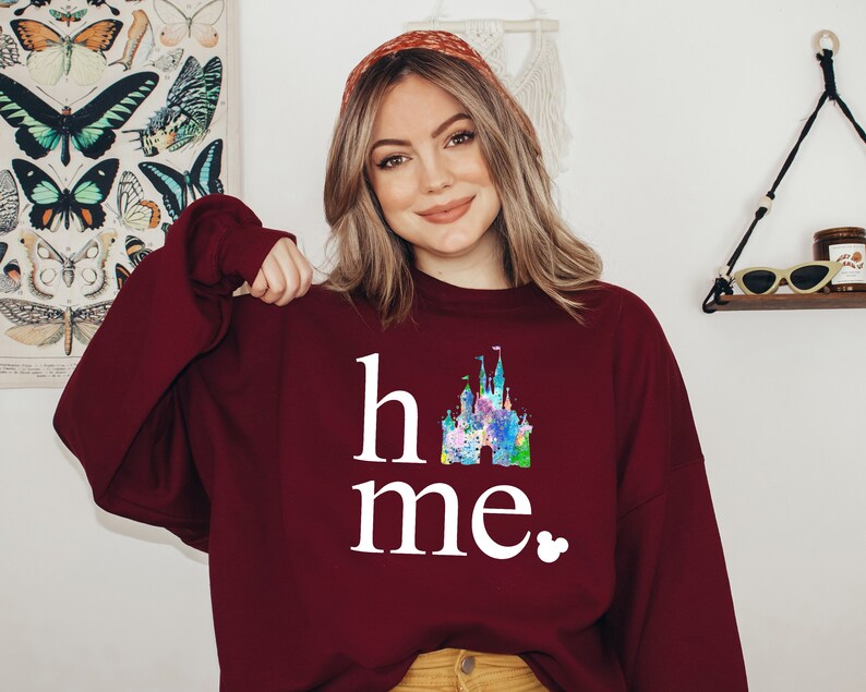 Puede incluir: Sudadera color burdeos con un gr&aacute;fico blanco de un castillo y el texto "home" y "me" con un peque&ntilde;o icono de Mickey Mouse.