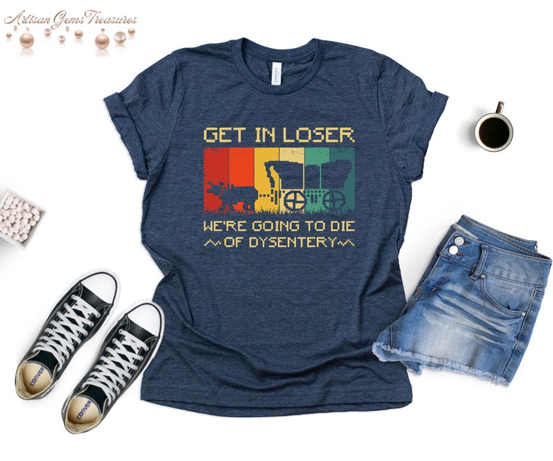 Op de afbeelding: Een marineblauw t-shirt met een vintage-stijl grafische afbeelding van een wagen en de tekst "GET IN LOSER WE'RE GOING TO DIE ~OF DYSENTERY~~"