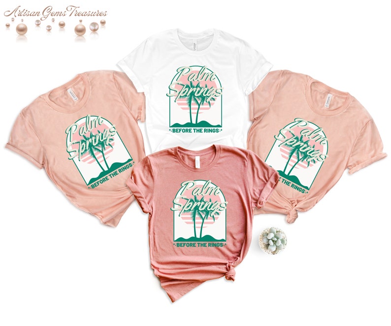 May include: Three t-shirts with a pink and green graphic design that says "Palm Springs" with palm trees and a sunset. The text below the graphic says "Before the Rings".