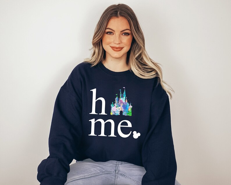 Puede incluir: Una sudadera azul marino con un gr&aacute;fico blanco de un castillo y el texto "home" y "me" con un peque&ntilde;o icono de Mickey Mouse.