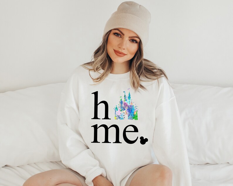 Puede incluir: Sudadera blanca con un gr&aacute;fico negro de un castillo de acuarela y el texto "home" con una cabeza de Mickey Mouse negra.