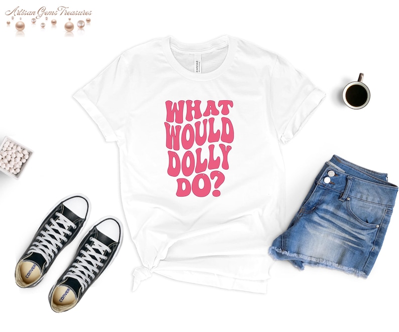 May include: White t-shirt with pink text that reads "What Would Dolly Do?" in a retro font.