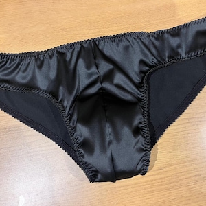 Sleek black satin men’s briefs with a soft stretch fit, lined pouch, and narrow elastic trim for a smooth, seductive silhouette, 28&quot; - 38&quot;.