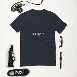 Puede incluir: Una camiseta azul marino oscuro con la palabra "FOMO" impresa en blanco en la parte delantera.