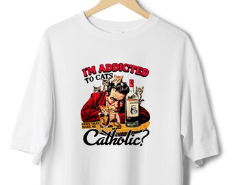 May include: White t-shirt with a graphic print of a man with cats and a bottle of whiskey. The text reads "I'm addicted to cats. Does that make me Catholic?"