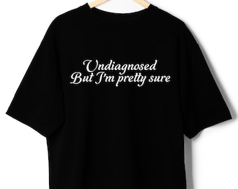 May include: Black t-shirt with white text that reads "Undiagnosed But I'm pretty sure"