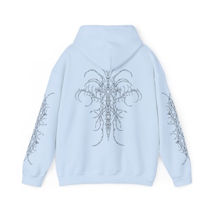 Pu&ograve; includere: Una felpa con cappuccio blu chiaro con un design grafico in bianco e nero sul retro e sulle maniche. Il design presenta una croce con dettagli intricati.
