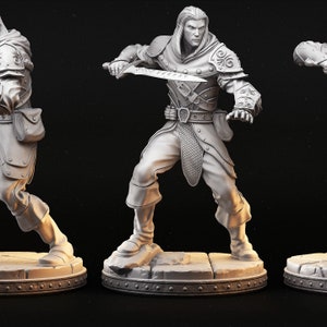 Op de afbeelding: Een wit 3D-geprint beeldje van een fantasy-personage. Het personage is een mannelijke mens met lang haar en een baard. Hij draagt een capuchon en een harnas. Hij houdt een zwaard in zijn rechterhand en een schild in zijn linkerhand. Het beeldje staat op een voetstuk.