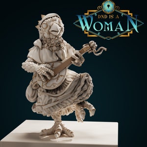 Pode incluir: Uma figurinha de cerâmica branca de uma criatura semelhante a um pássaro tocando um alaúde. A criatura está vestindo um vestido branco e tem uma coroa na cabeça. A figurinha está em pé sobre uma base branca. O texto "DND IS A WOMAN" está no fundo.