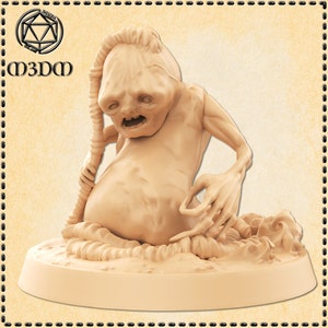 Może przedstawiać: Miniatura wydrukowana w 3D w kolorze beżowym, przedstawiająca groteskową, humanoidalną istotę z długim, cienkim ogonem. Istota ma dużą głowę z szerokimi ustami i wypukłymi oczami. Siedzi na podstawie z fakturowaną powierzchnią.