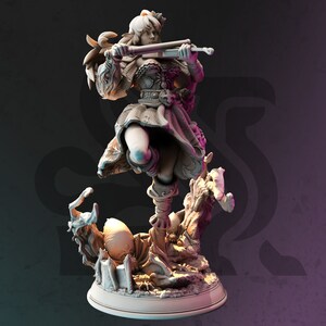 May include: A white painted figurine of a woman playing a violin, standing on a base with a tree and an egg. The woman is wearing a flowing dress and has long hair.