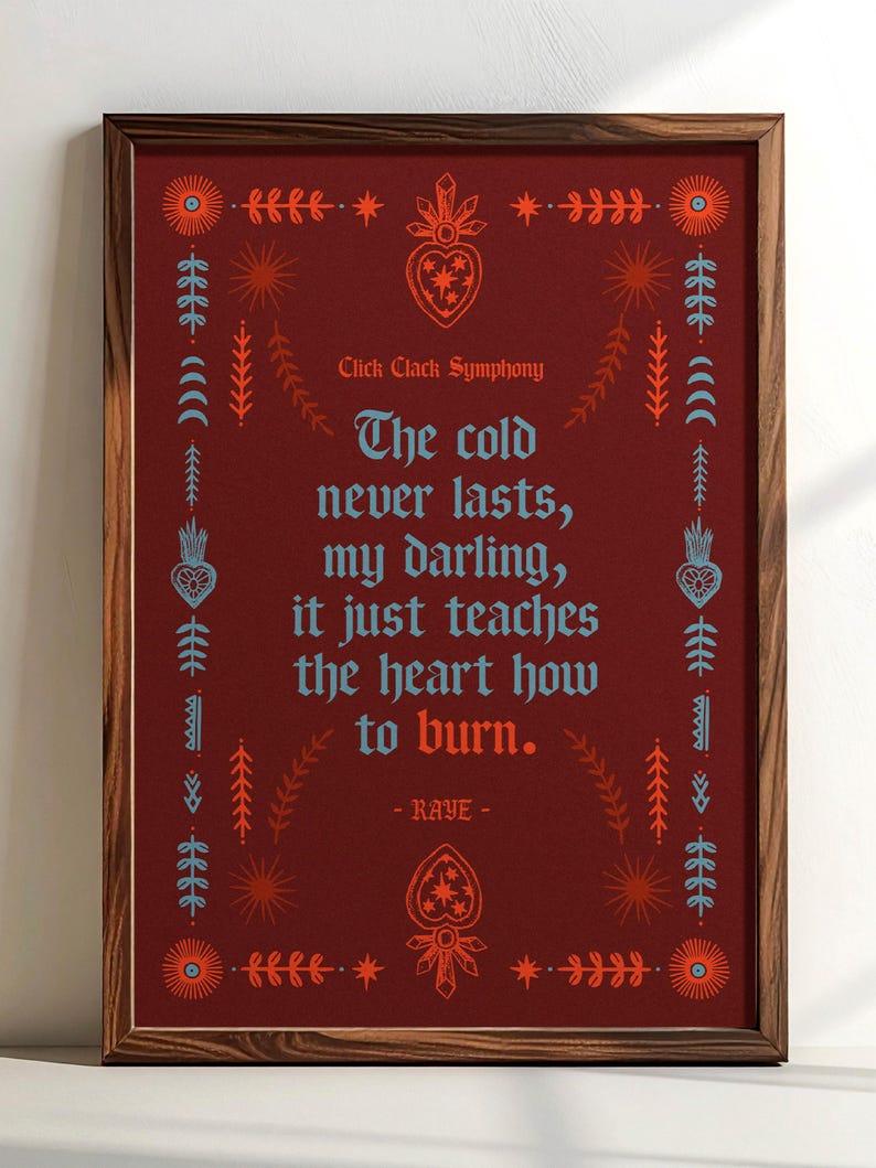 May include: Framed art print with a dark red background and a wooden frame. The print features a quote in blue and orange text, surrounded by decorative floral and geometric designs. The text reads "The cold never lasts, my darling, it just teaches the heart how to burn."