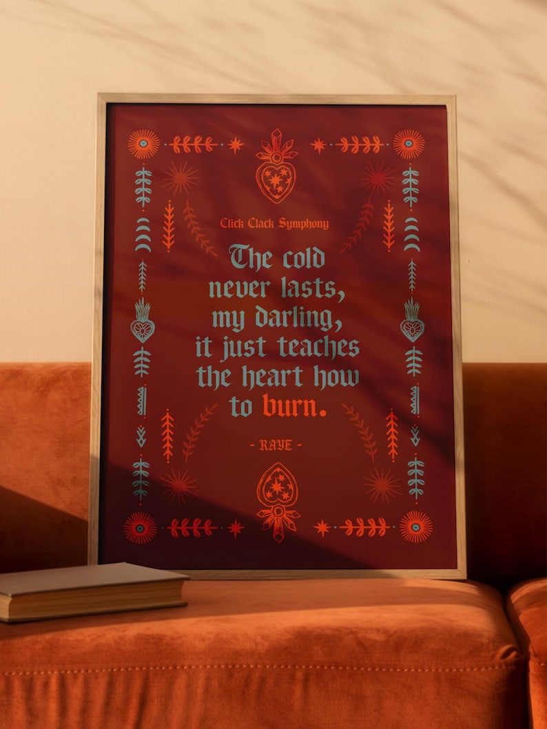 May include: Framed art print with a burgundy background and decorative floral and geometric elements. The text reads "The cold never lasts, my darling, it just teaches the heart how to burn." by RAYE.
