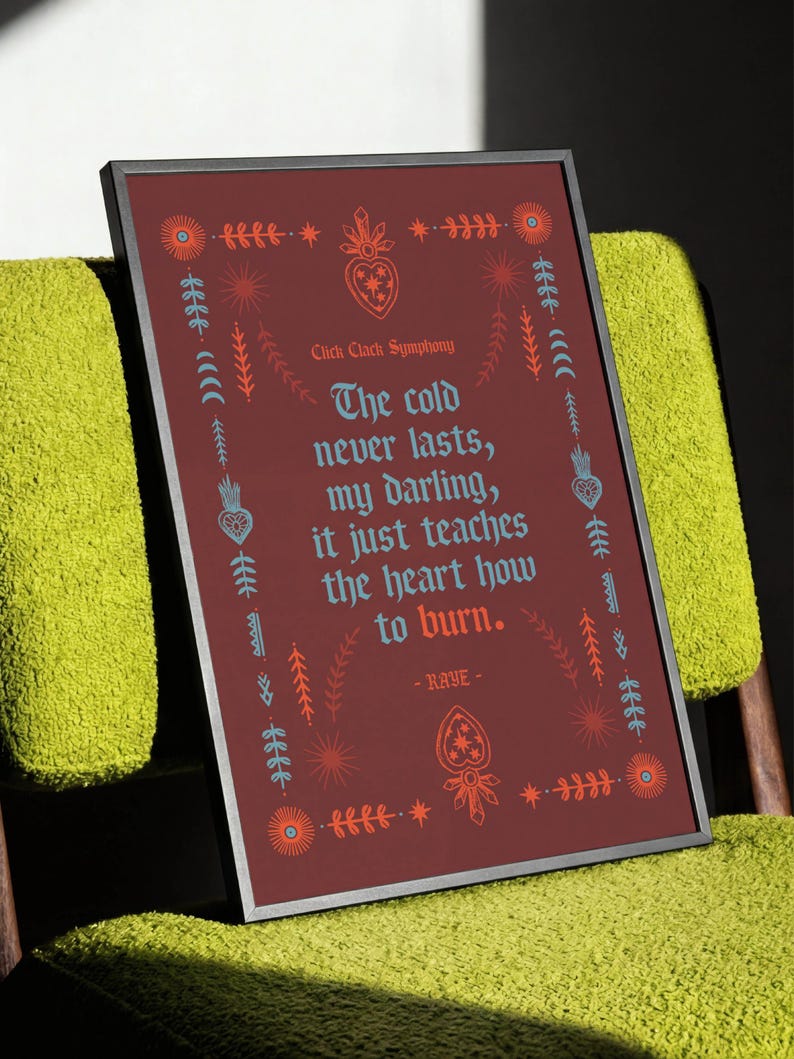 May include: Framed art print with a burgundy background and decorative floral and star motifs. The text reads "The cold never lasts, my darling, it just teaches the heart how to burn." The artist is RAYE.