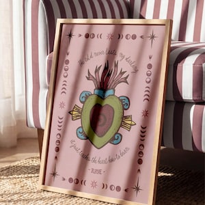 May include: A framed print with a pink background features a heart-shaped design with a red and green color scheme. The text "The cold never lasts, my darling. It just teaches the heart how to burn. - RAYE-" is written around the design. The frame is made of wood.