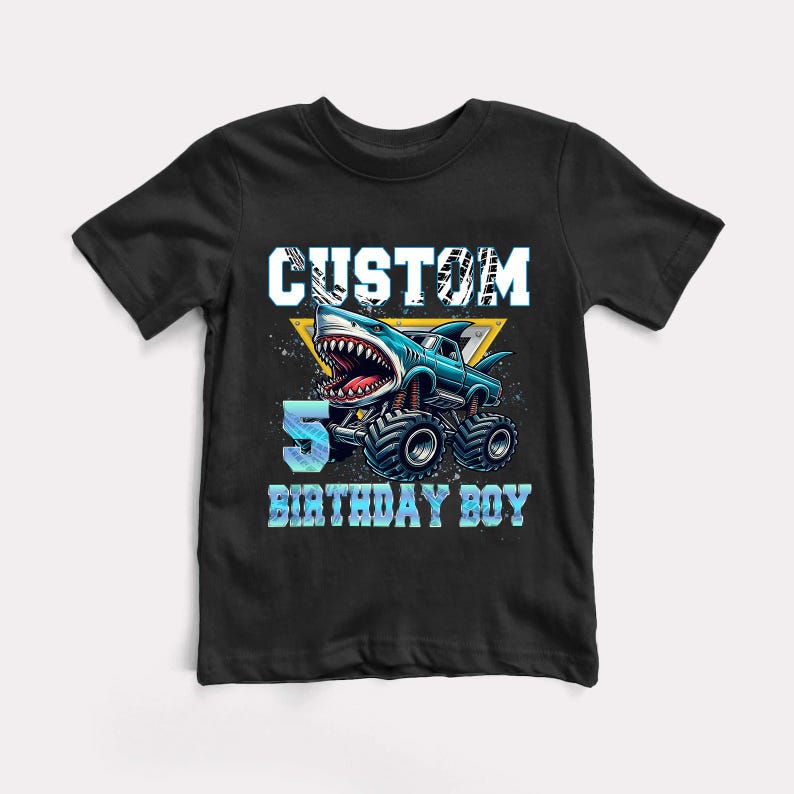 May include: Black t-shirt with a blue monster truck with a shark head and the text "CUSTOM 5 BIRTHDAY BOY" in white.
