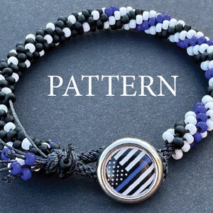 May include: A black, white, and blue beaded bracelet with a thin black cord and a silver charm featuring a thin blue line American flag. The bracelet is on a gray background and the word "PATTERN" is written in white text.